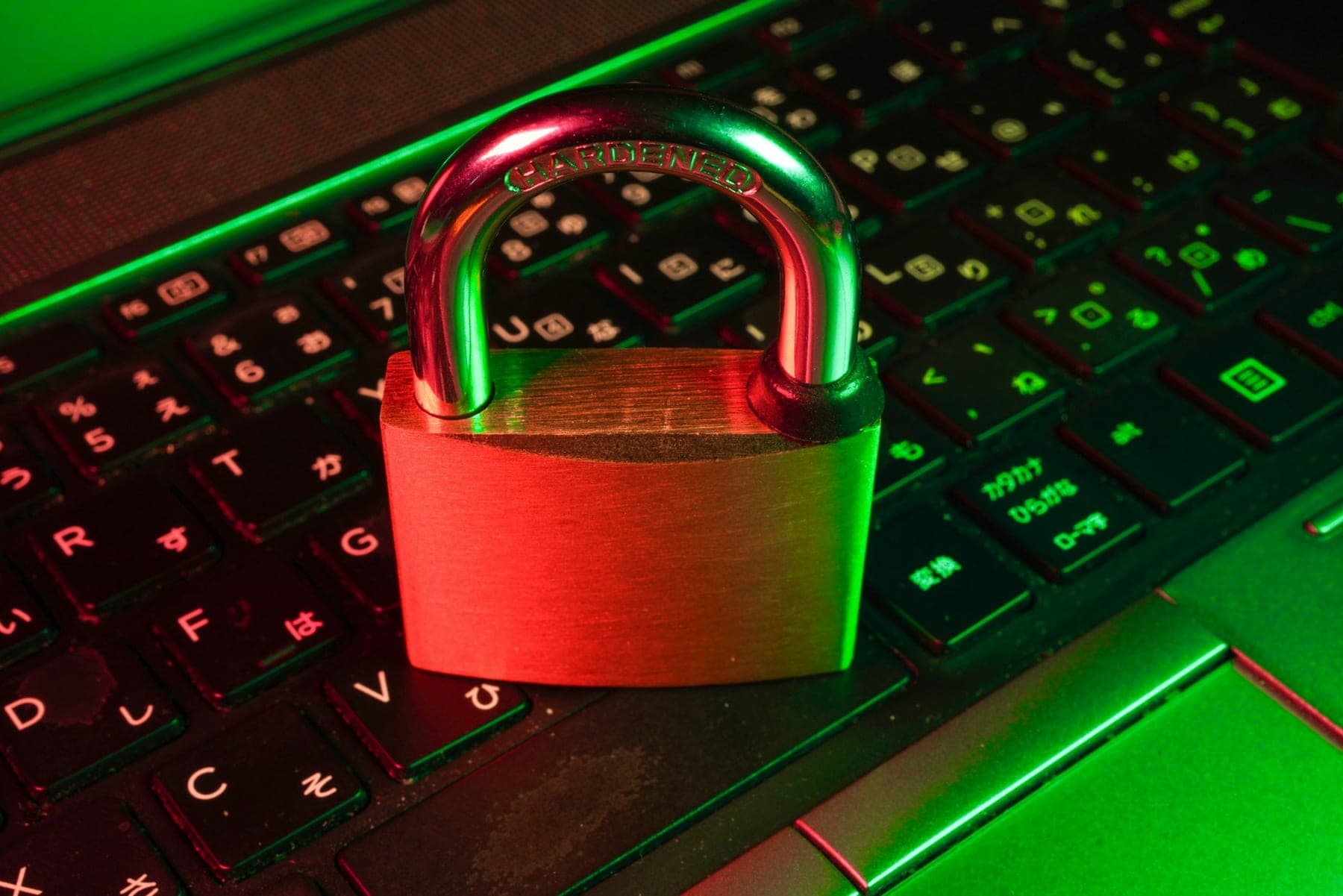 A padlock resting on a laptop keyboard, lit in red and green