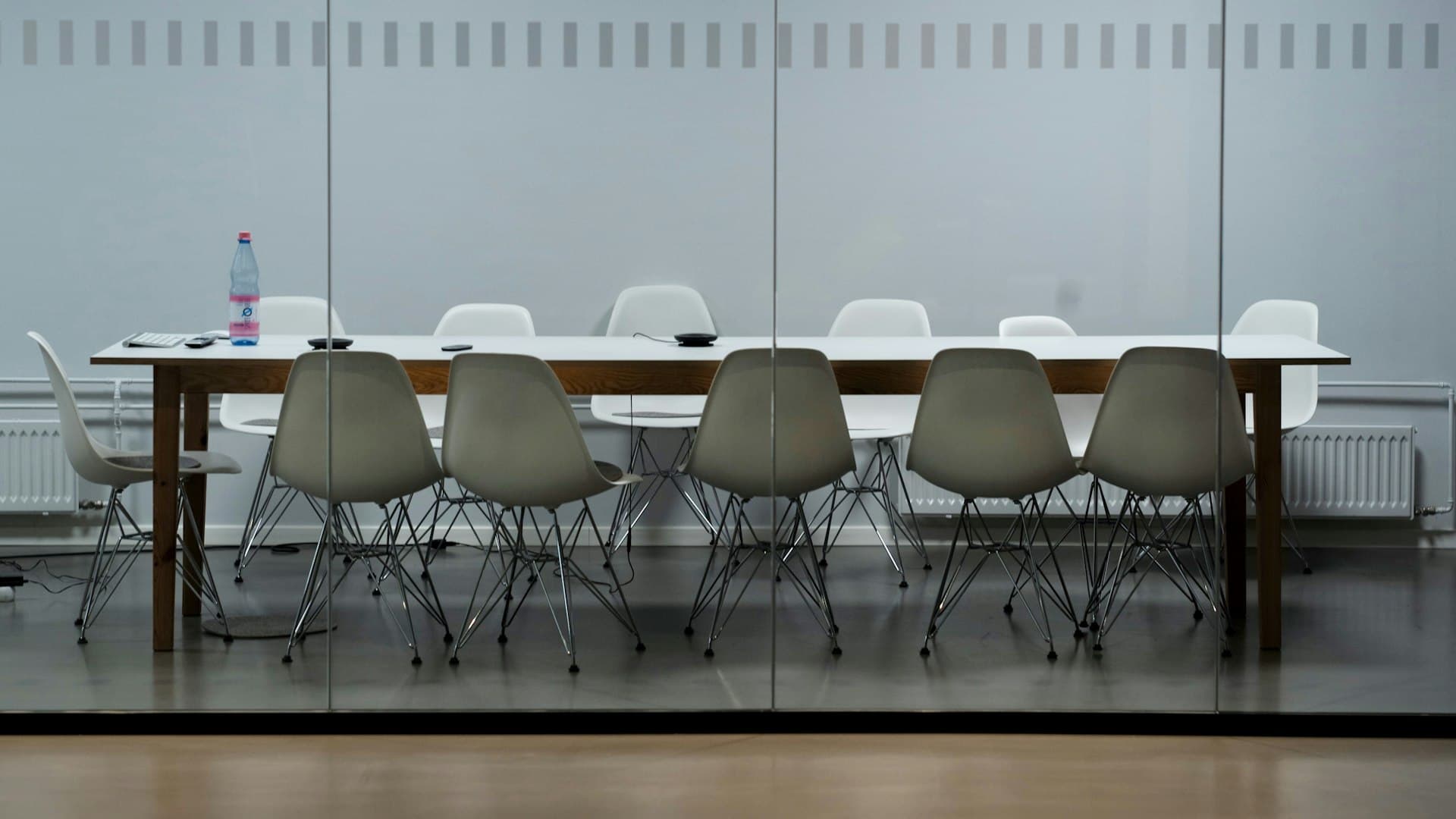 Modern glass-walled boardroom with empty chairs around a table