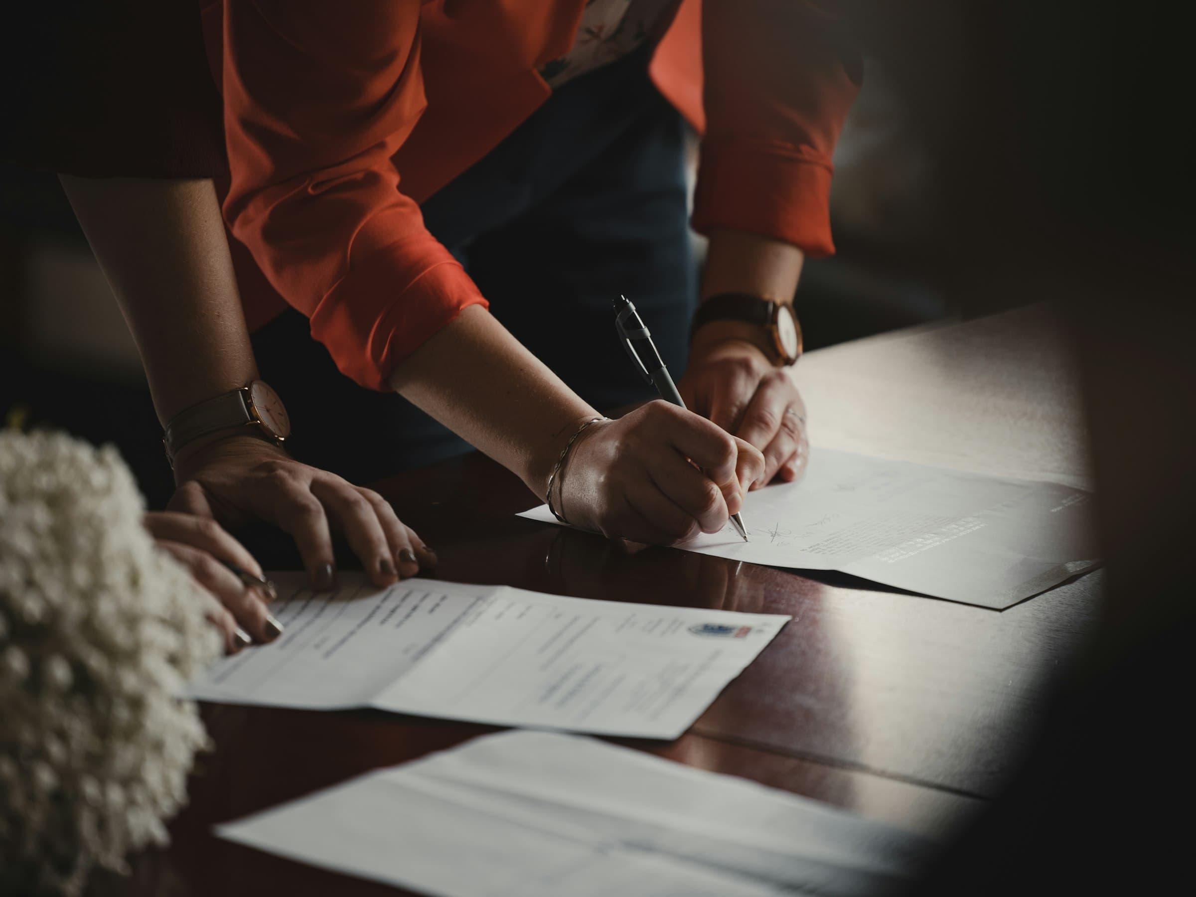 Close-up of hands reviewing and signing compliance documents